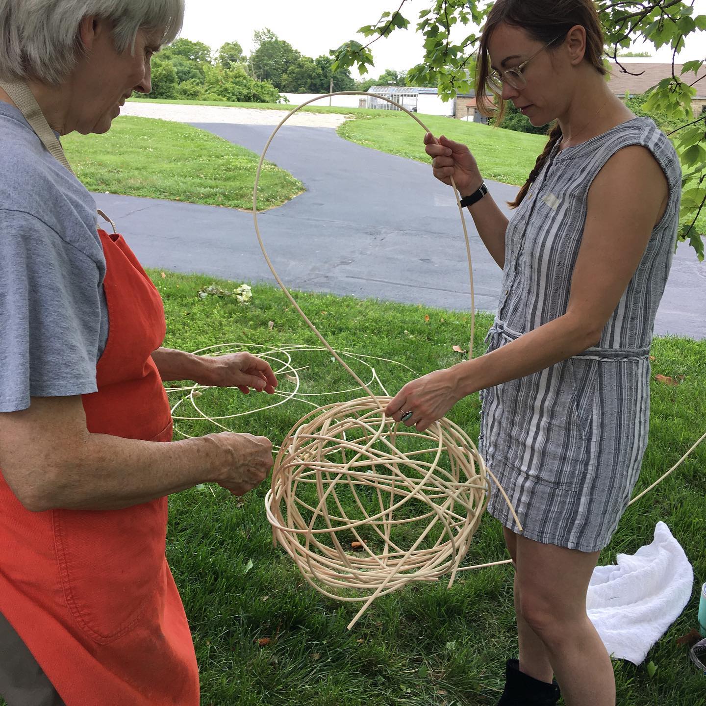 Two women weaving an orb